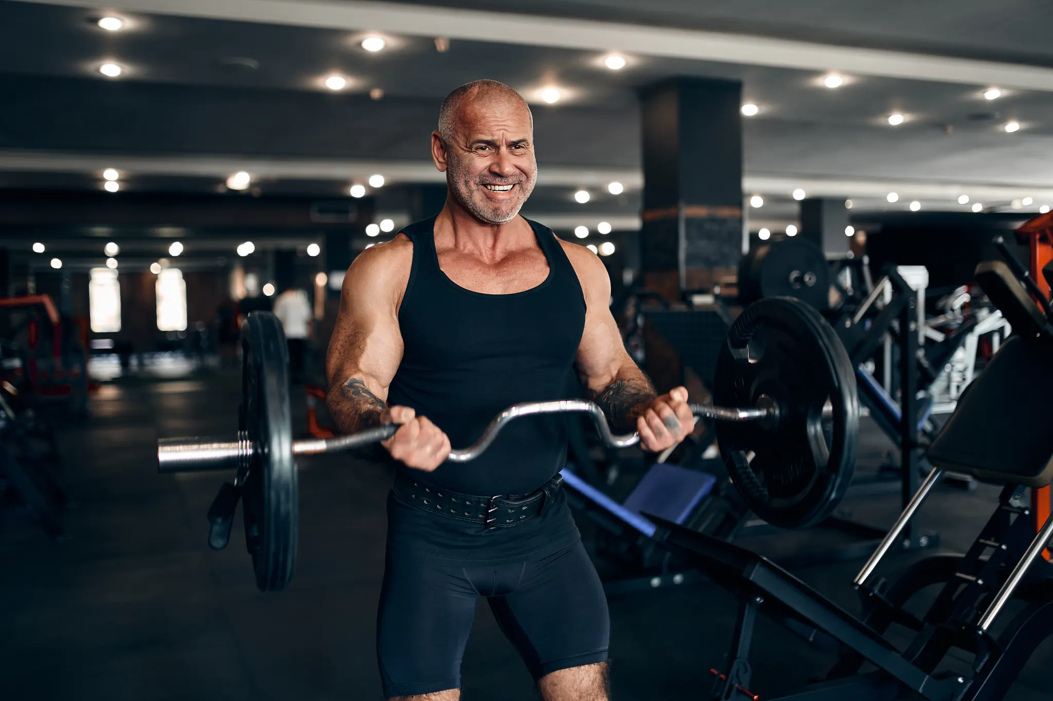 Older man curling a barbell in the gym